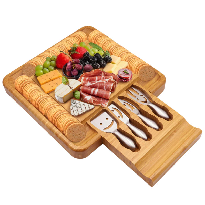 Bamboo cheese board with charcuterie on top and stainless steel utensils