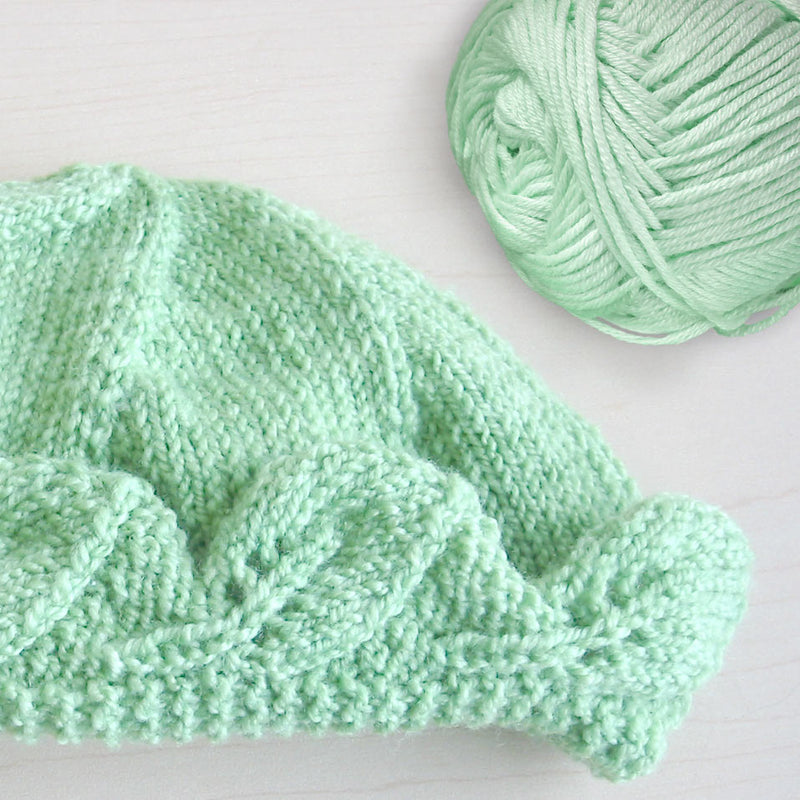 a knitted hat next to the yarn that was used to knit it