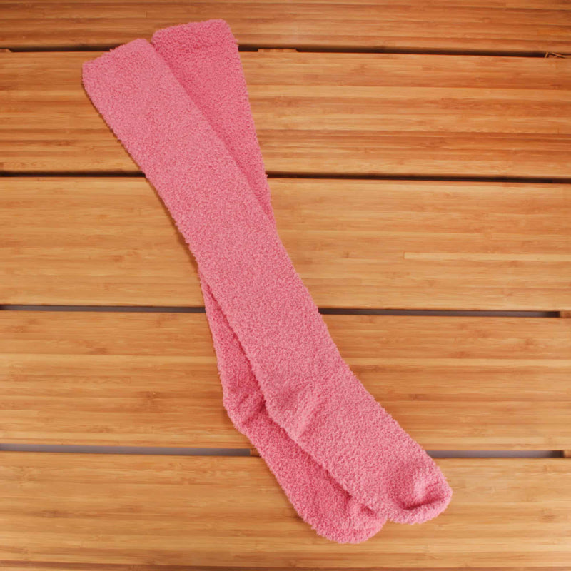 A pair of our pink fuzzy knee high socks laying on a cool harwood floor